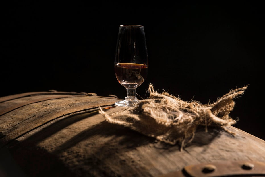 A glass of whisky sitting on a Gordon and MacPhail whisky cask